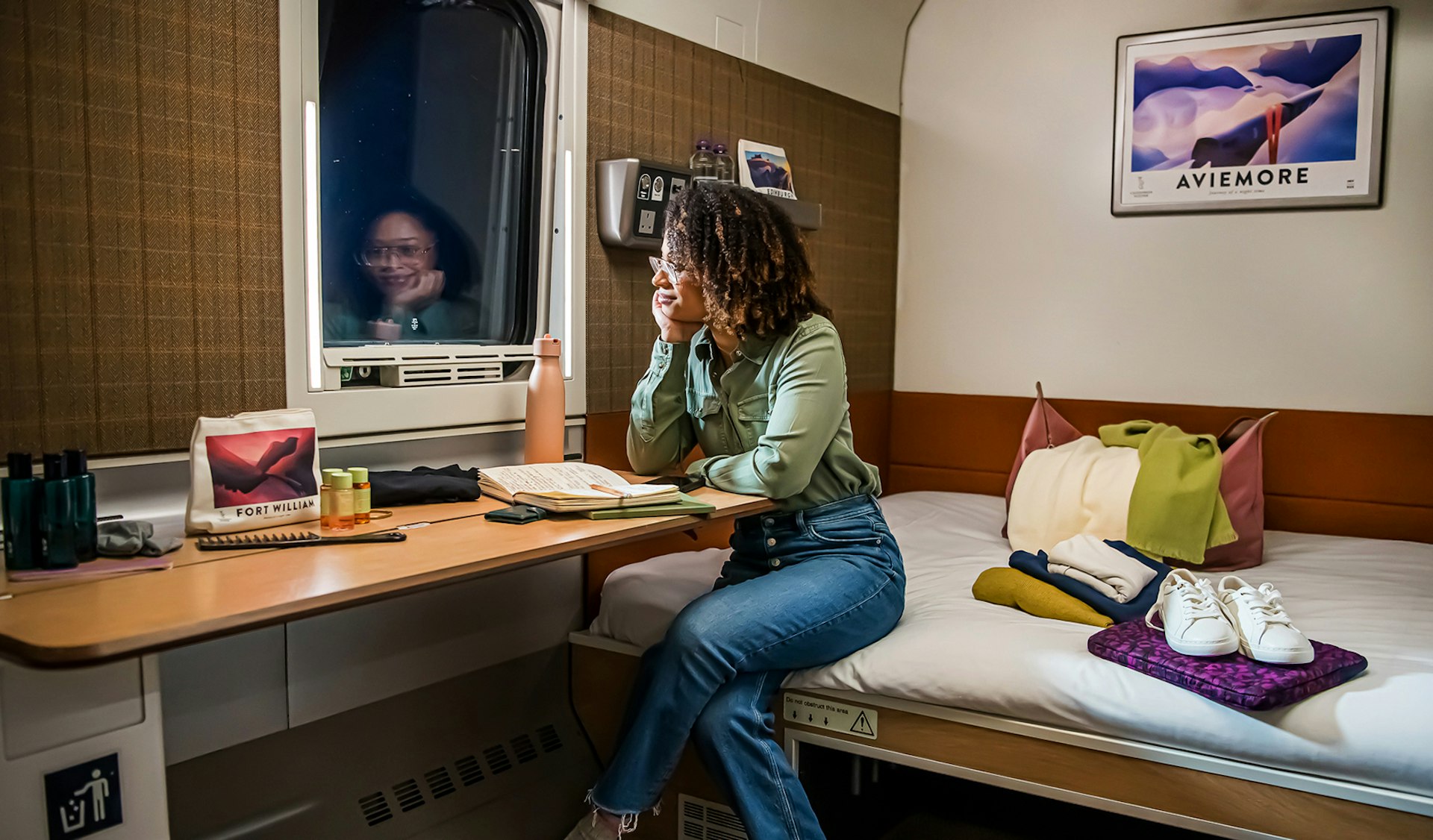 A woman looks out the window in a Caledonian Double room aboard the Caledonian Sleeper overnight train between London and Scotland