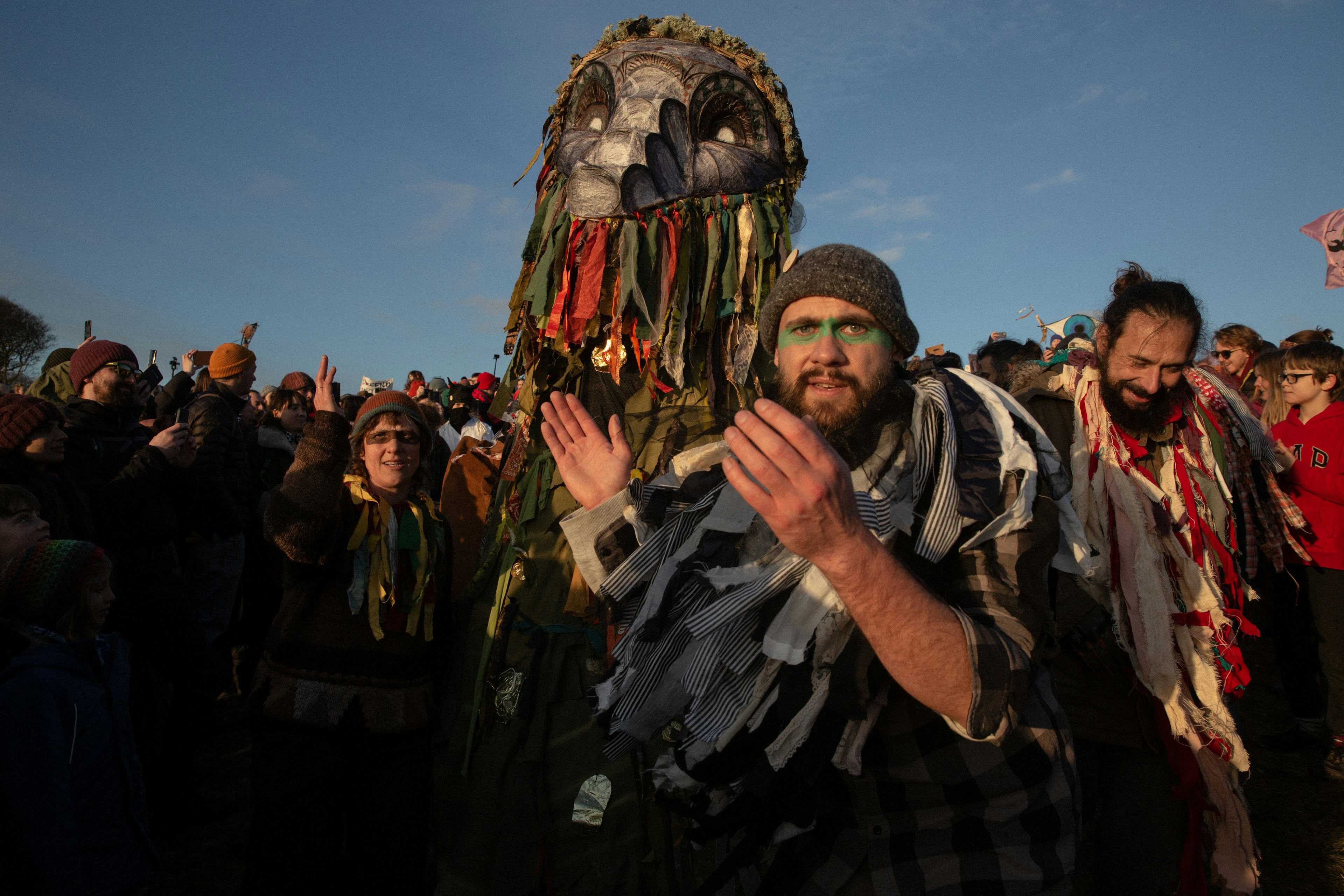 A man dressed up in folk clothes claps at a protest in England.