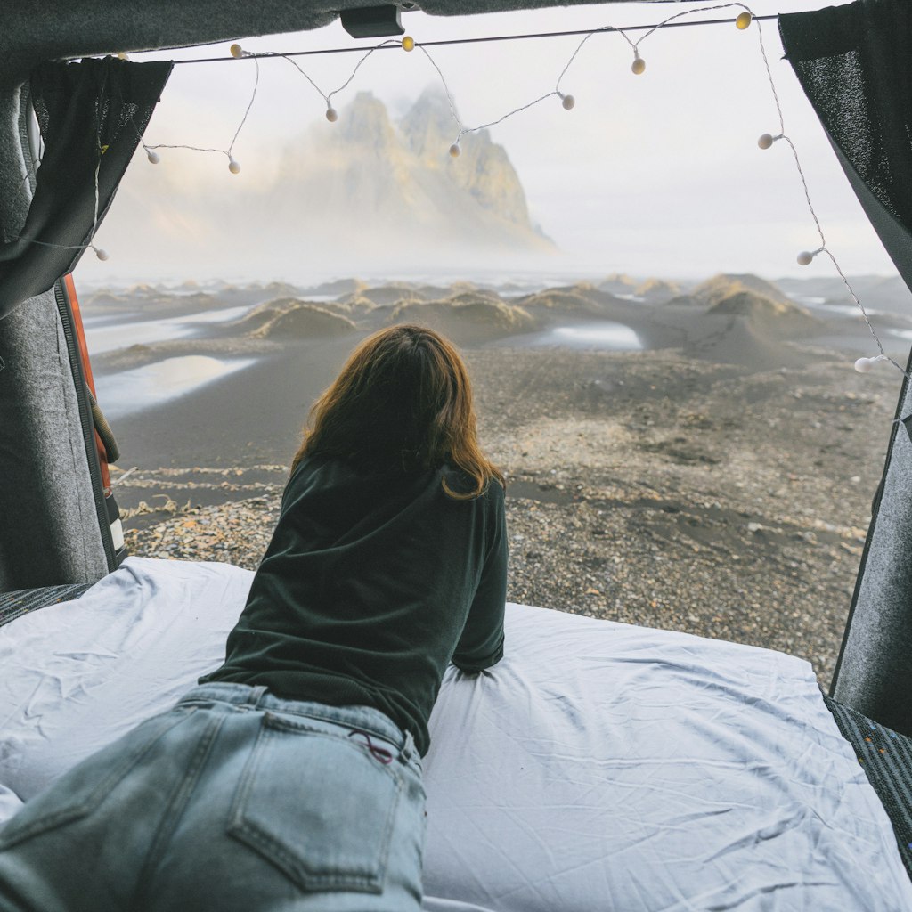 Young Caucasian woman  looking at Vestrahorn mountains from camper van