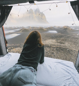 Young Caucasian woman  looking at Vestrahorn mountains from camper van