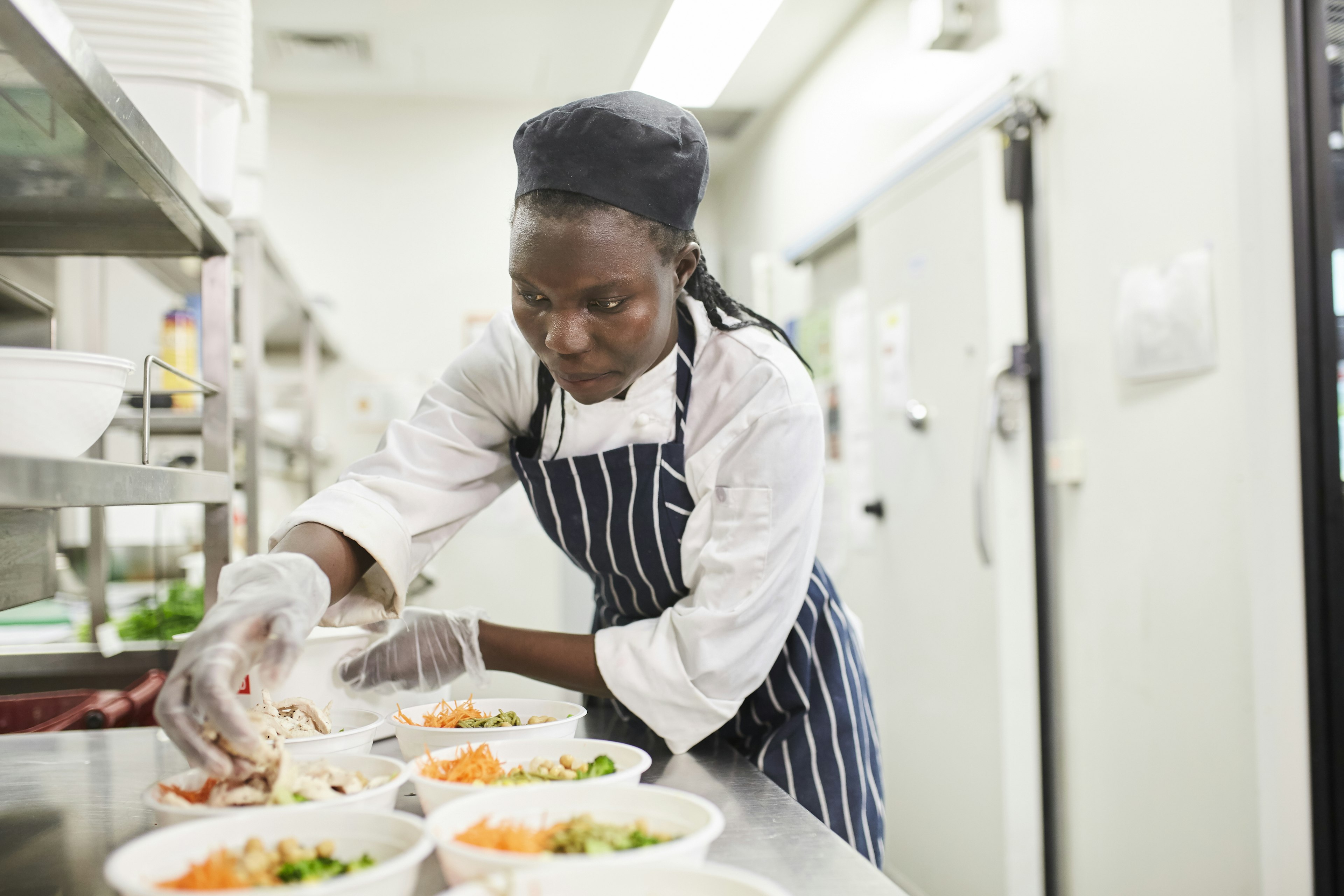 A woman of African descent prepares food in the kitchen of a restaurant, Melbourne, Victoria, Australia