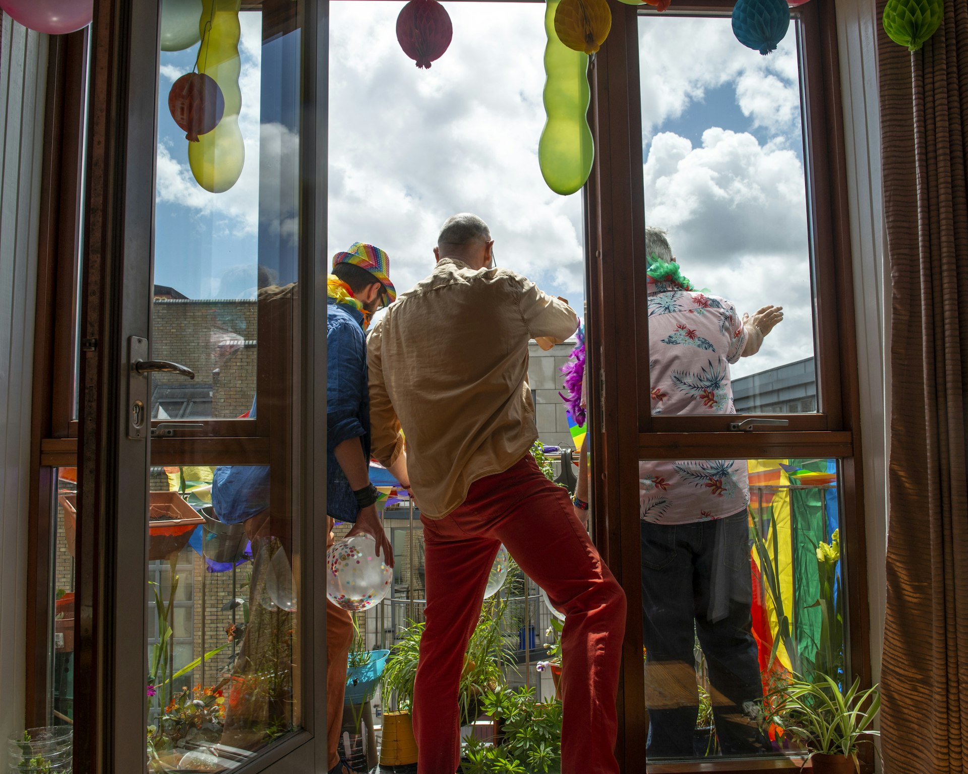 Grupo de gays celebrando o Orgulho Gay em casa, na varanda