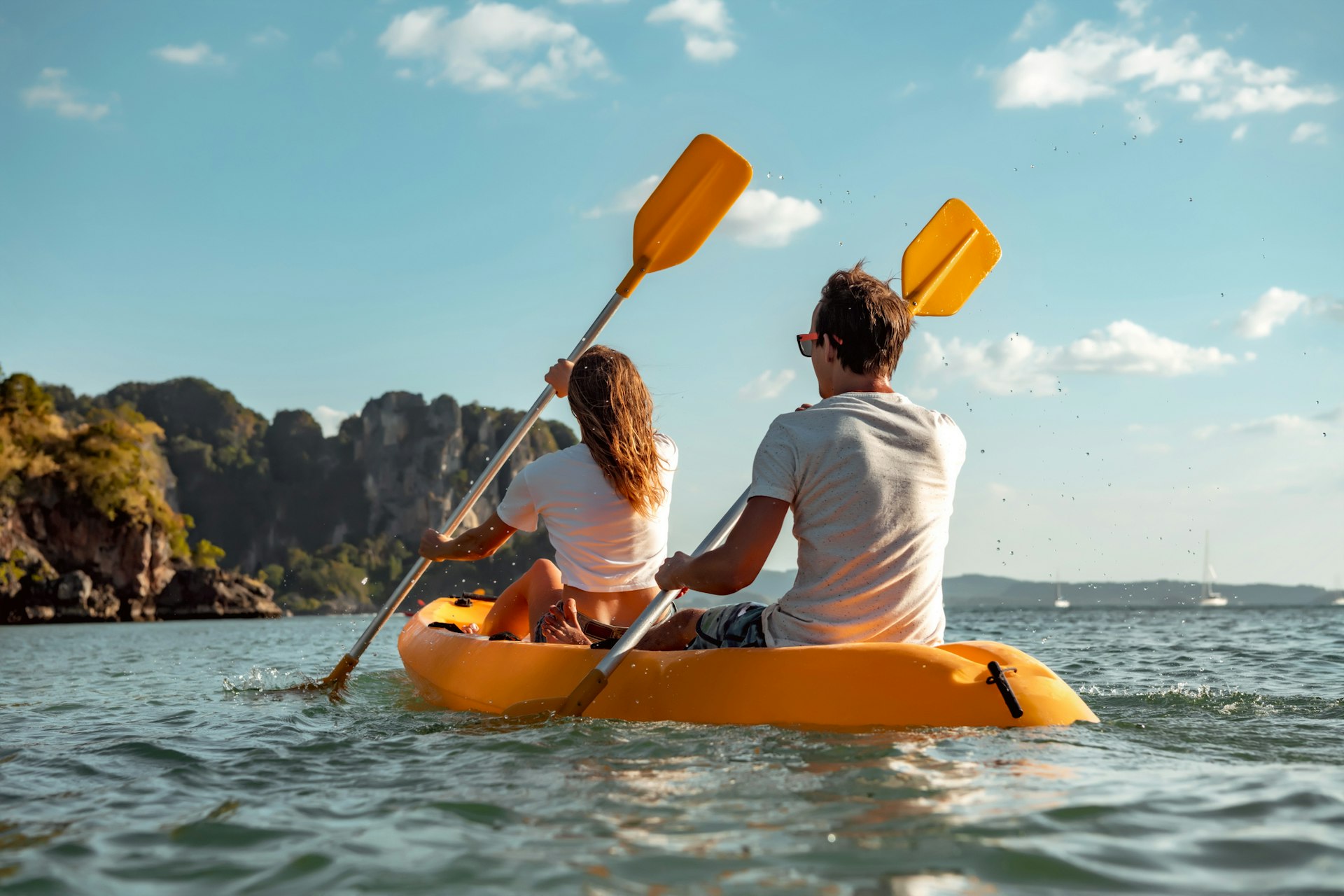 Sea kayaking or canoeing concept with young couple kayakers at tropical bay. 