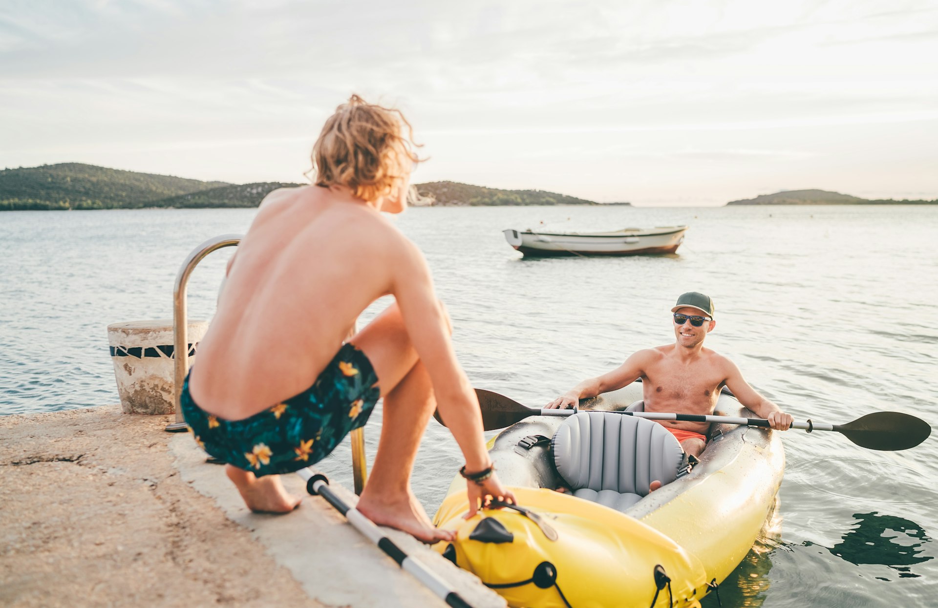 A father and his teenager son on a bright yellow inflatable kayak returning back from an evening ride in the Adriatic Sea near Šibenik, Croatia