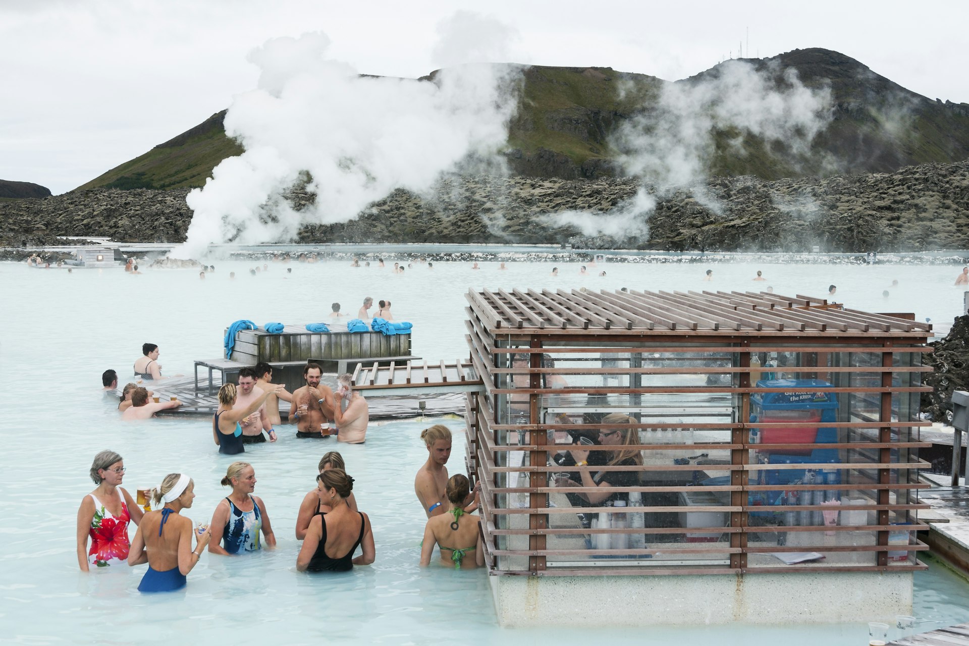 Tourists drinking and socializing or waiting in line at the pool bar floating in the mineral waters at the Blue Lagoon 