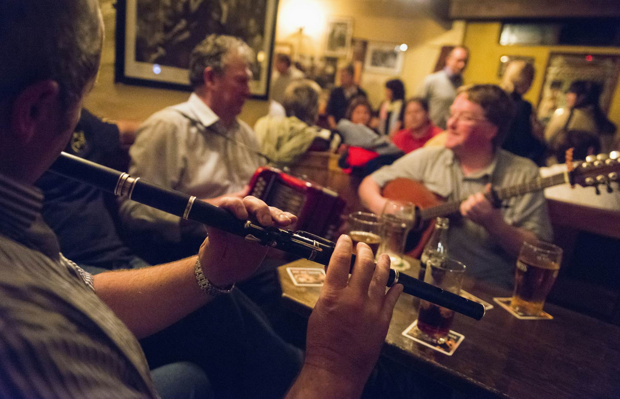 Musicians play wind and string instruments in a busy pub