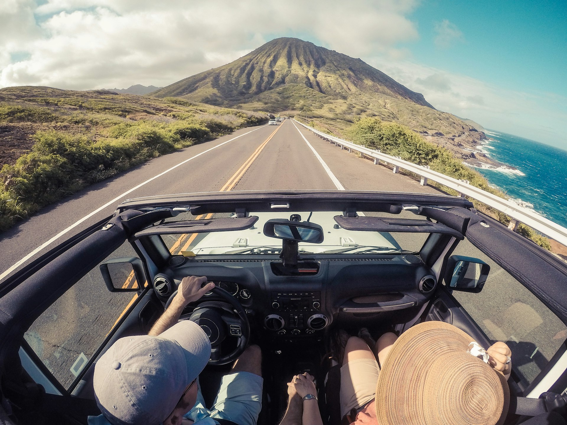 couple driving in Hawaii in a convertible, image taken from above  by Getty Images/RooM RF