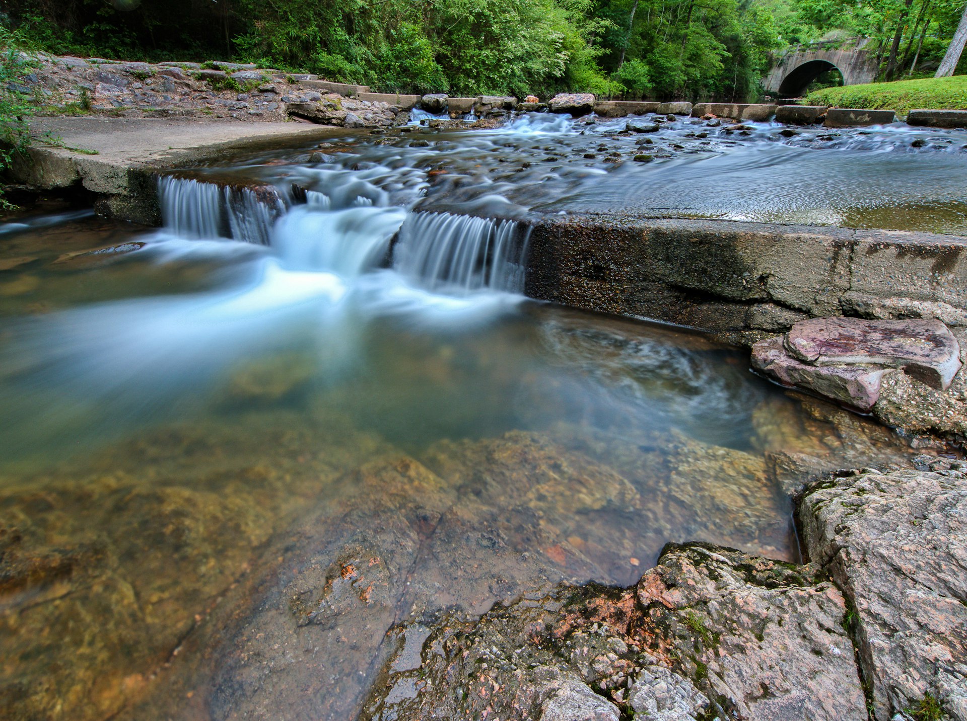 A tranquil waterfall and stream running through a wooded area 