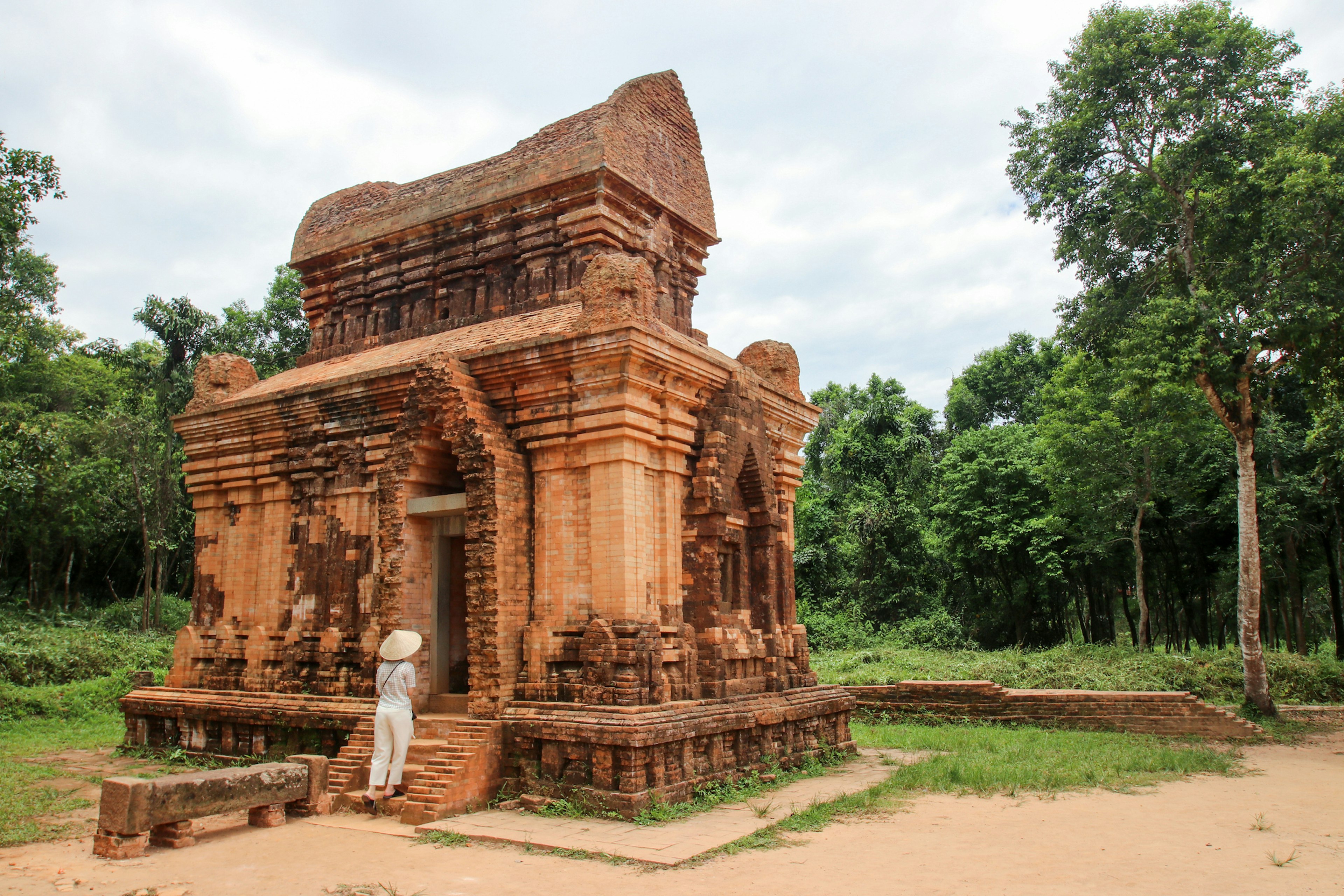 A woman approaches a ruin surrounded by jungle