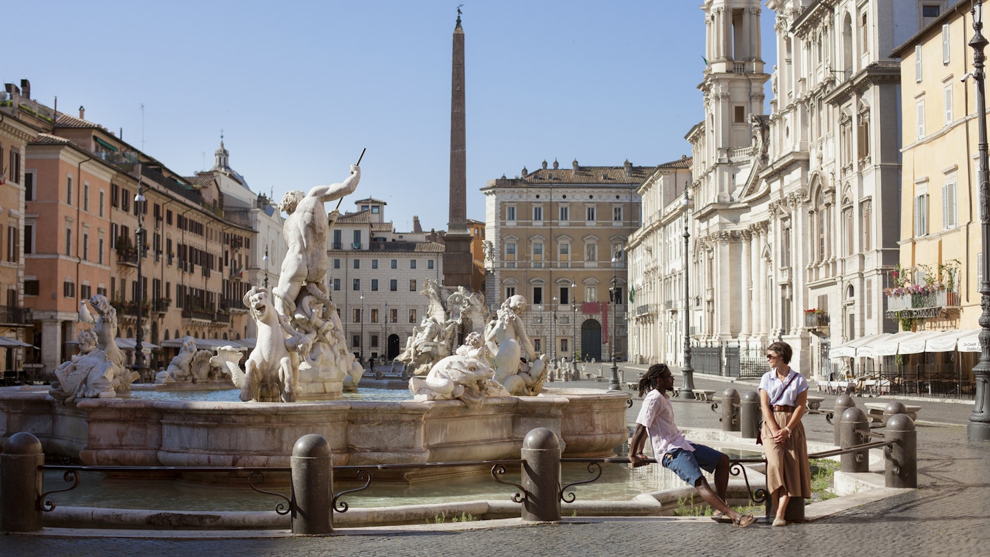 1267302487
Man and woman at Bernini fountain in beautifully deserted Piazza Navona, Rome, Italy