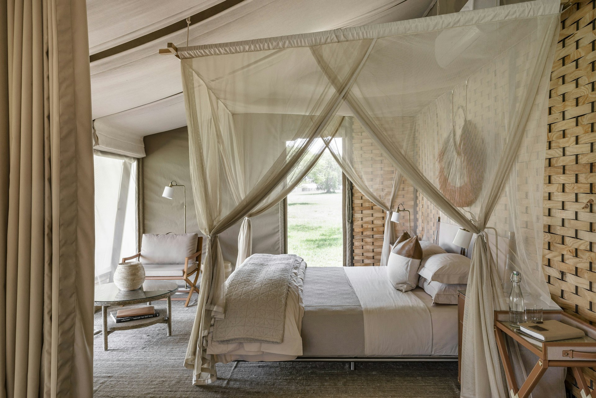 A tented safari lodge bedroom with sheer draperies surrounding the bed