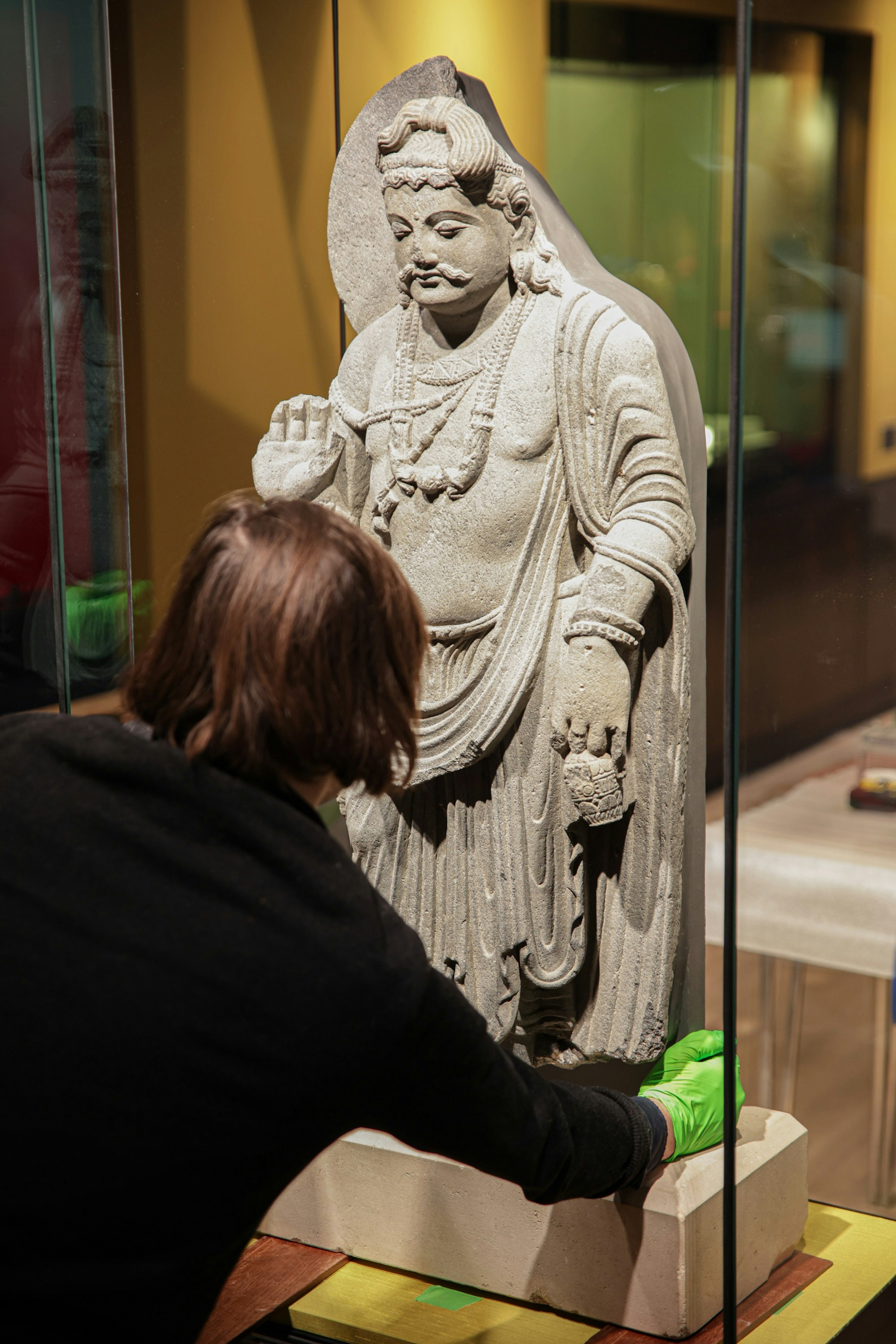 A woman works to install a South Asian exhibit in a museum.