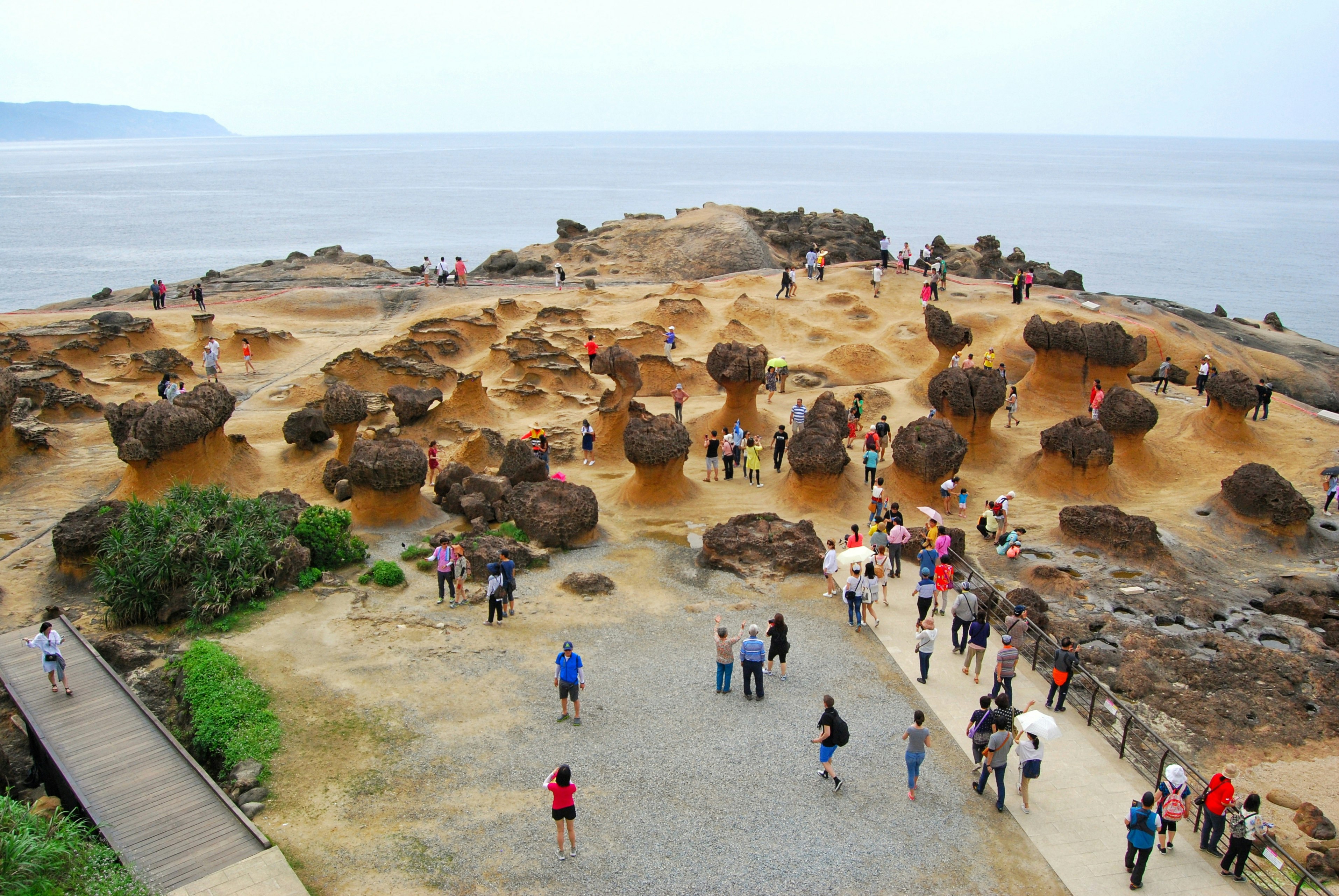 An aerial shot of tourists looking at the unusually shaped rocks, eroded by the ocean, at Yehliu Geopark, Taiwan