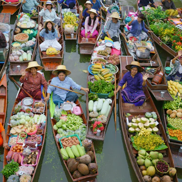 Crowded wooden boats in canal with fruits, vegetables, foods and grocery products for sell and trade by villagers at Tha Kha traditional floating market.