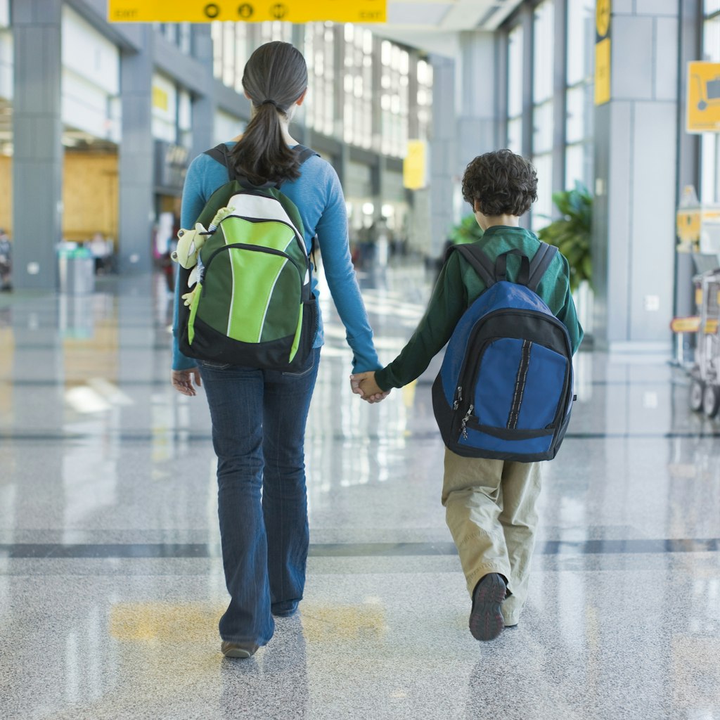 Kids holding hands walking in airport terminal