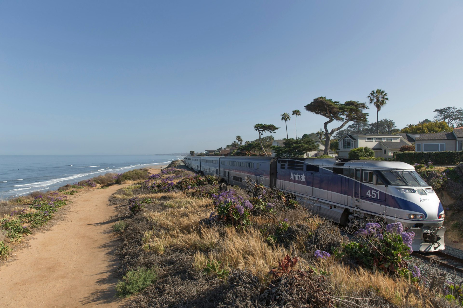 An Amtrak Surfliner train passes a beach and the Pacific Ocean, California, USA