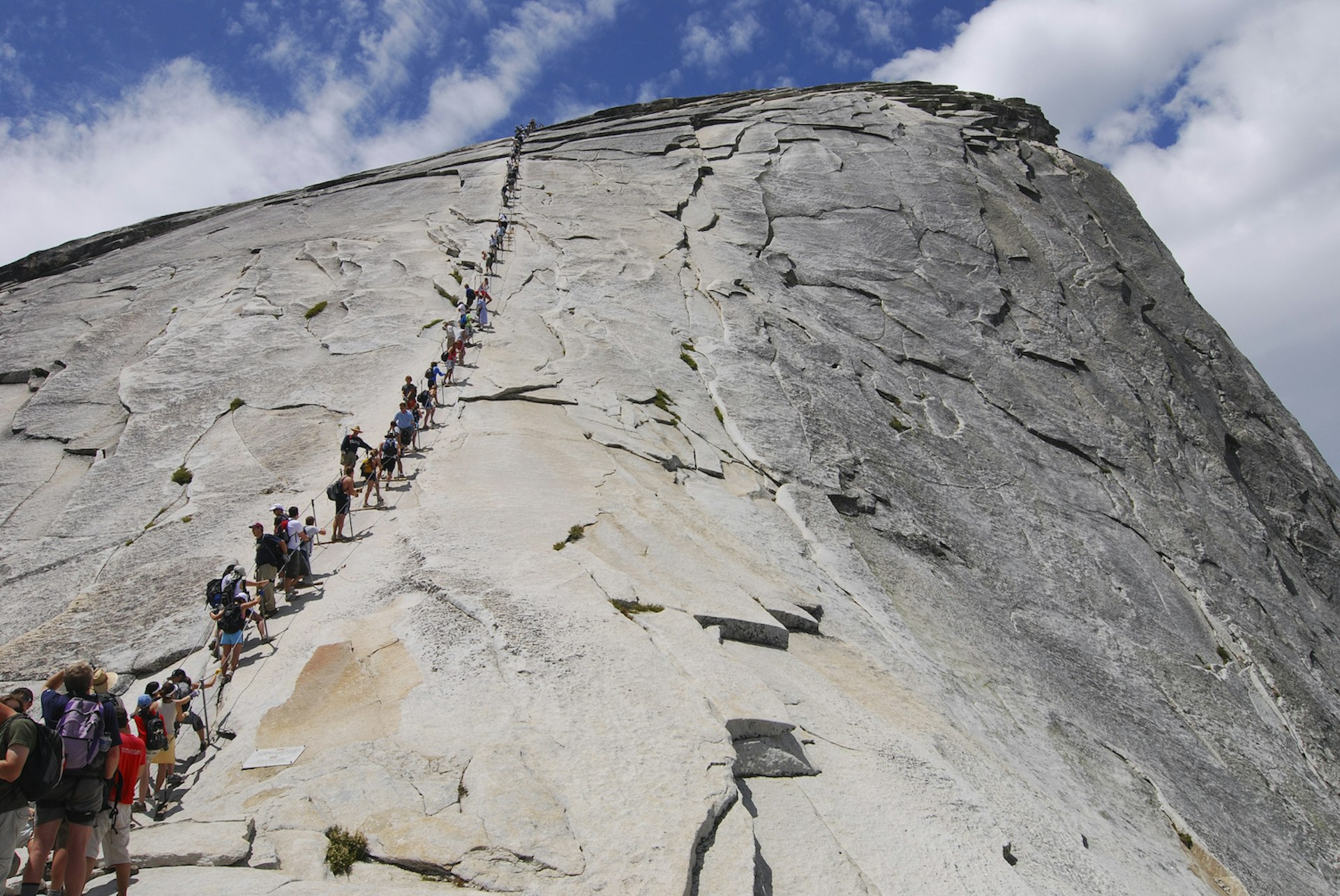 A line of hikers ascends to the top of Half Dome, Yosemite National Park, California, USA