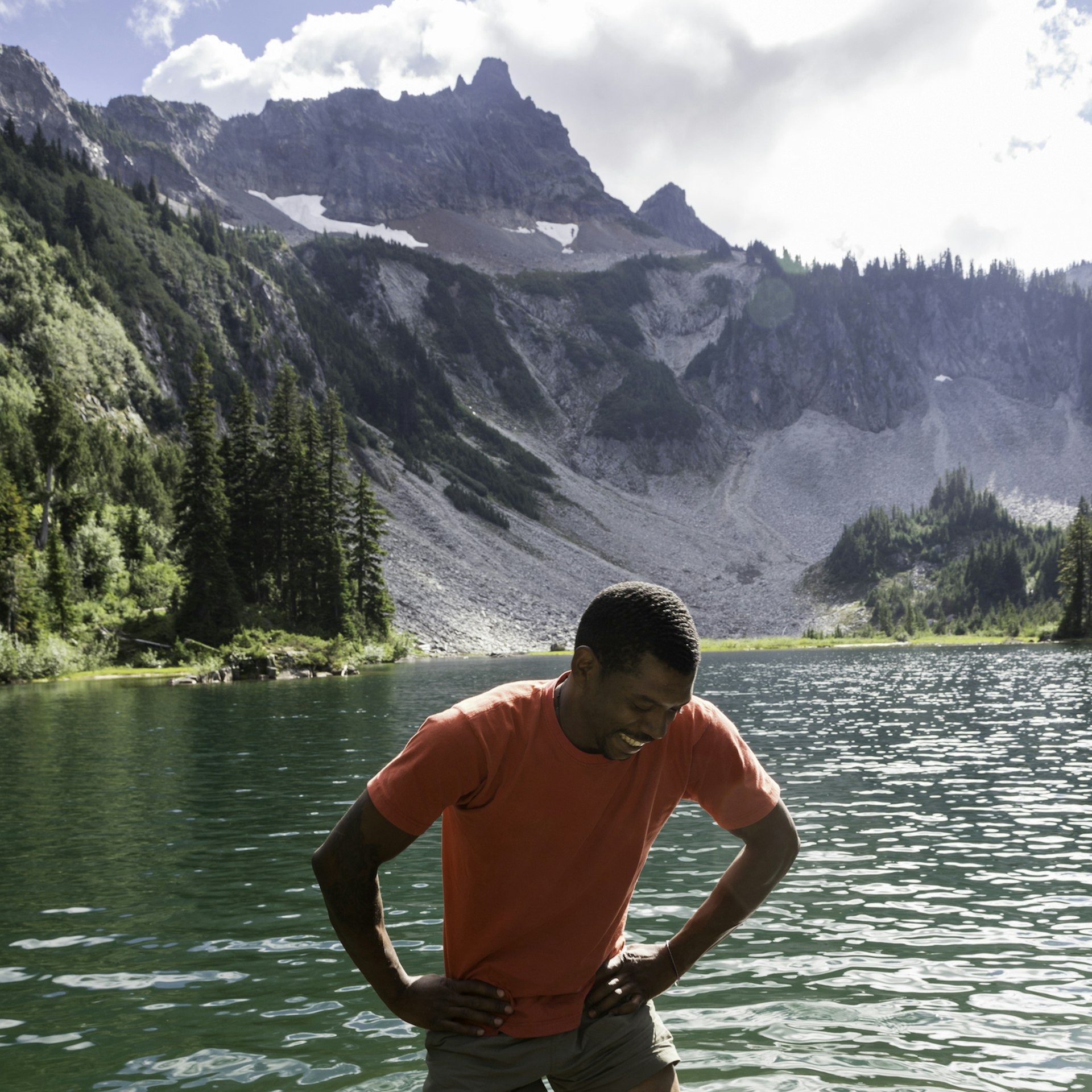 A happy man smiles while wading in a cold alpine lake in Mount Rainier National Park, Washington State, USA