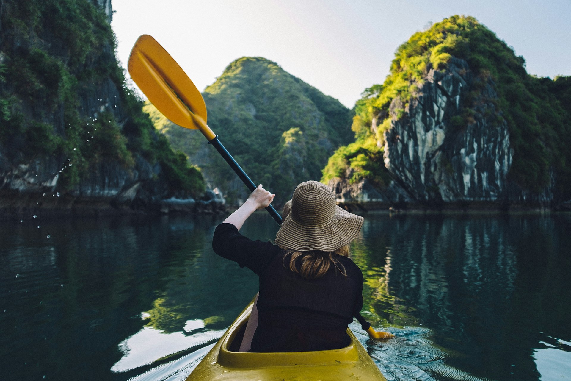 Rear View Of Woman Kayaking In Lake Against Mountain