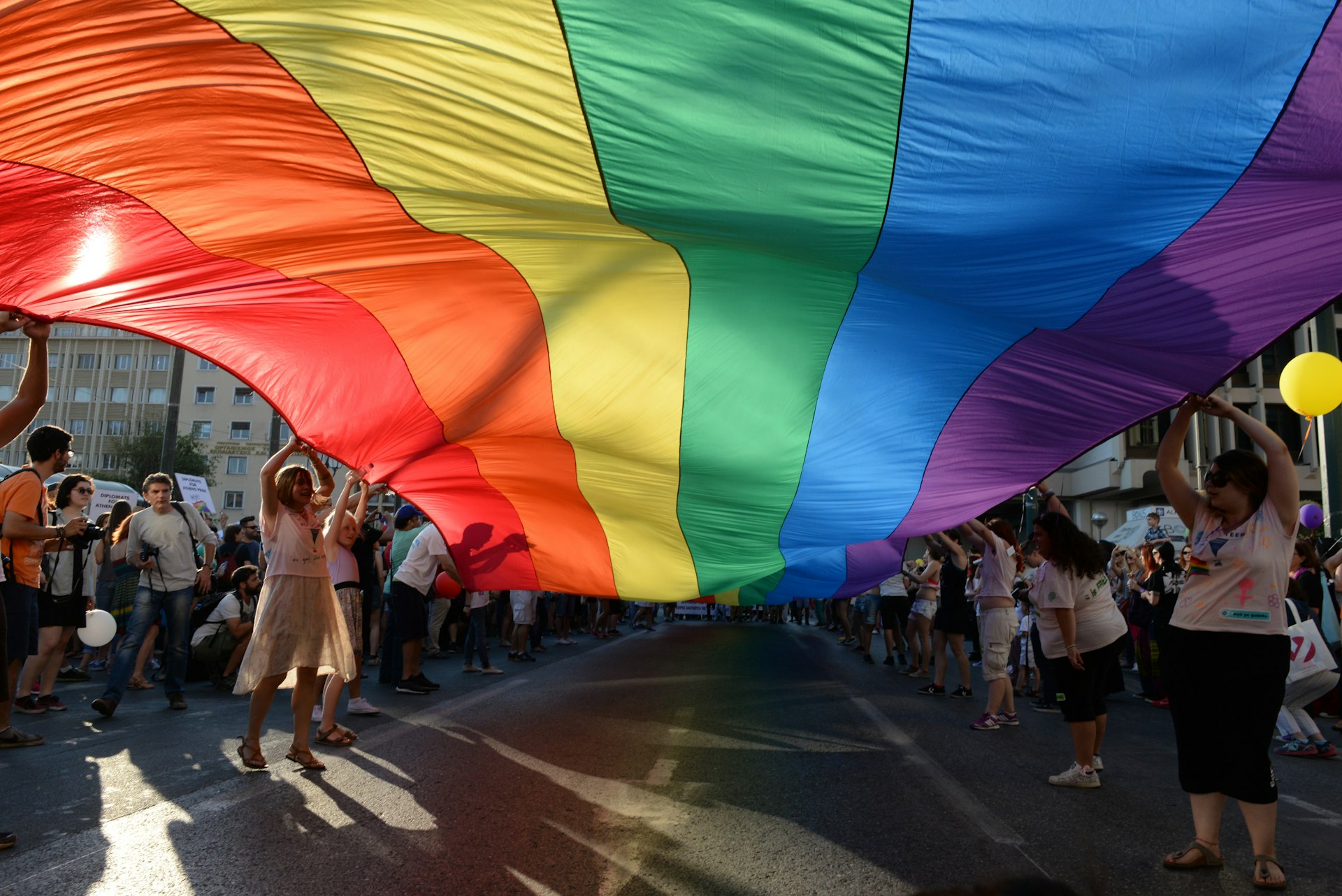 Participants lift a giant rainbow flag above the street during the annual Gay Pride parade event in central Athens.