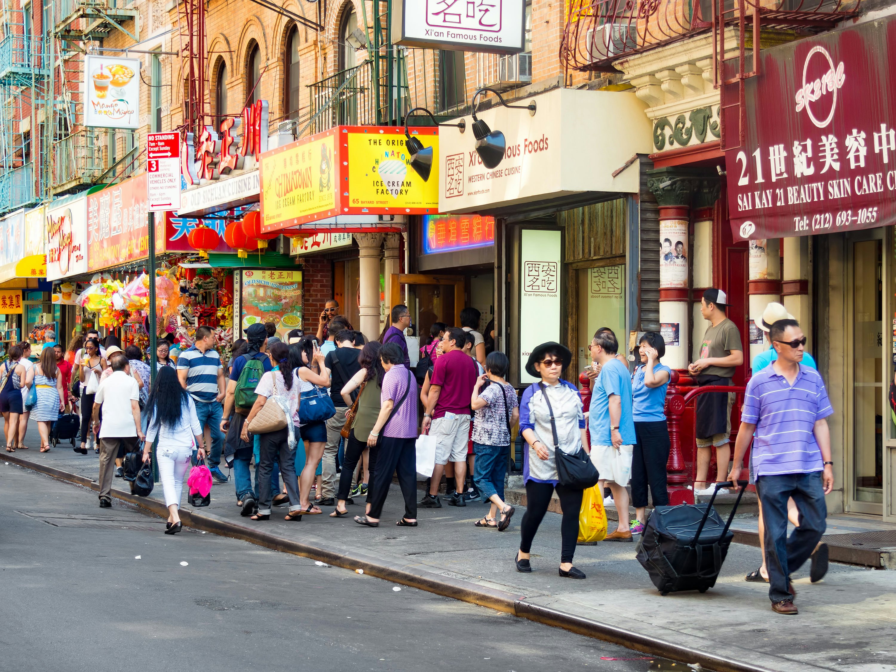 People walk in front of businesses in Chinatown, Manhattan, New York City, New York, USA