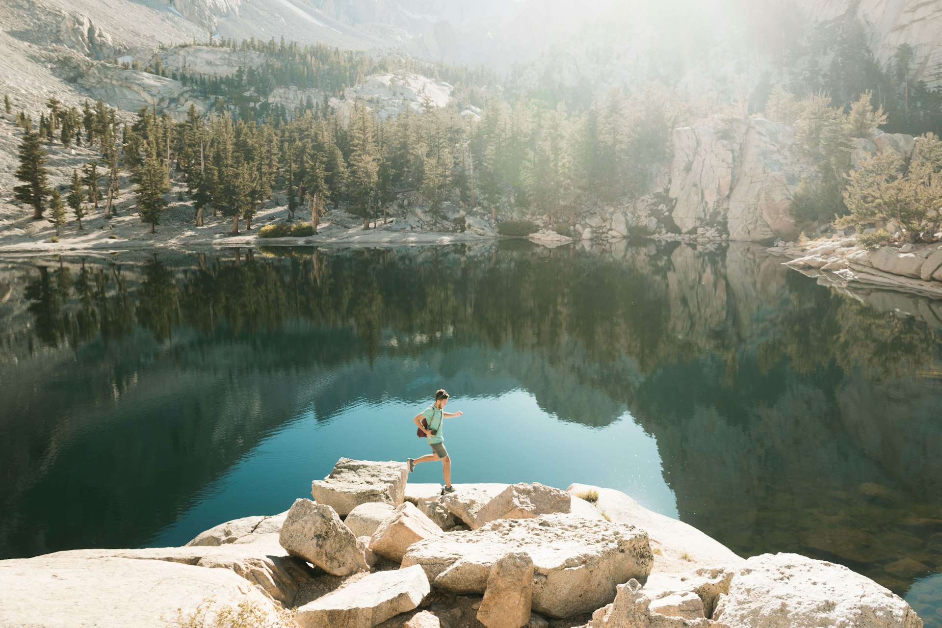 A young sporty man runs and jumps on the rocks next to Mirror Lake in Yosemite