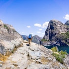 A person seen from behind, hiking on the shoreline of Hetch Hetchy reservoir in Yosemite National Park, Sierra Nevada mountains, California. The reservoir is one of the main sources of drinking water for the San Francisco bay.