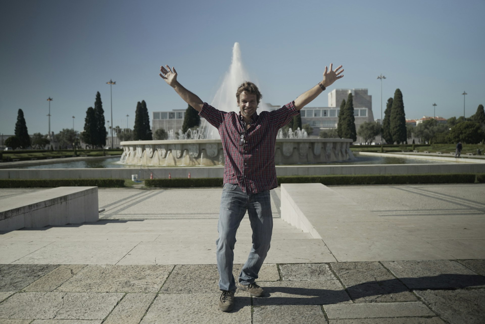 A man, Tiago, jumps in front of a fountain in Lisbon. 