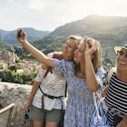 Multi generation family sightseeing beautiful town of Valldemossa. Sunny summer day in Majorca, Spain...Teenage girl, mother and grandmother are taking selfies. Behind them there is a magnificent view of the town of Valldemossa and the surrounding mountains - Serra de Tramuntana...Canon R5
1346146237