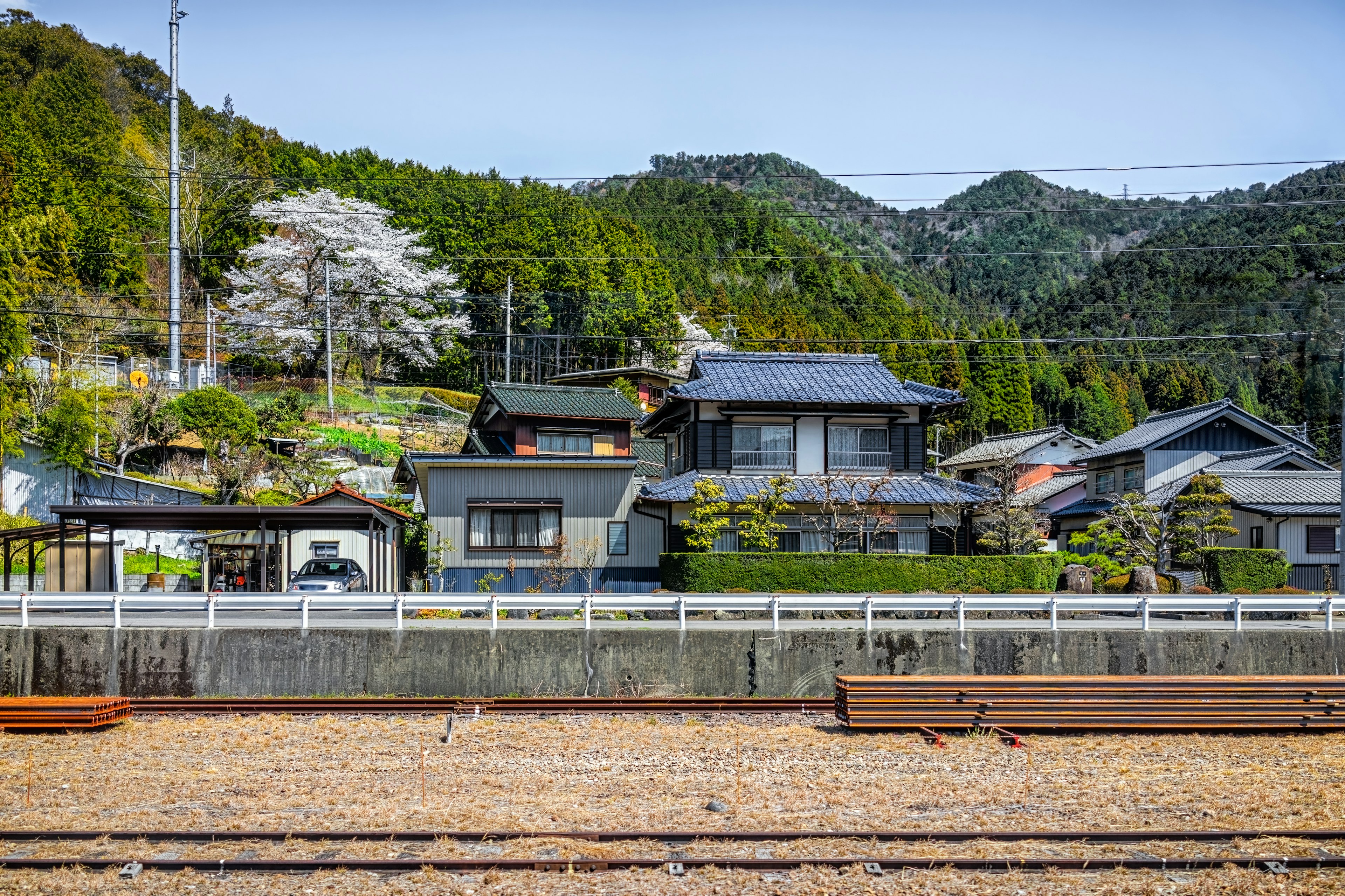 A view of Gero Onsen village from the train tracks with cherry blossoms and mountains, Japan