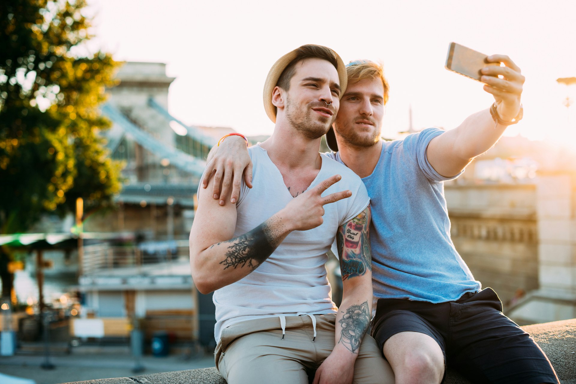 Young gay men on city break in early summer, visiting Budapest, cuddling and taking a selfie together