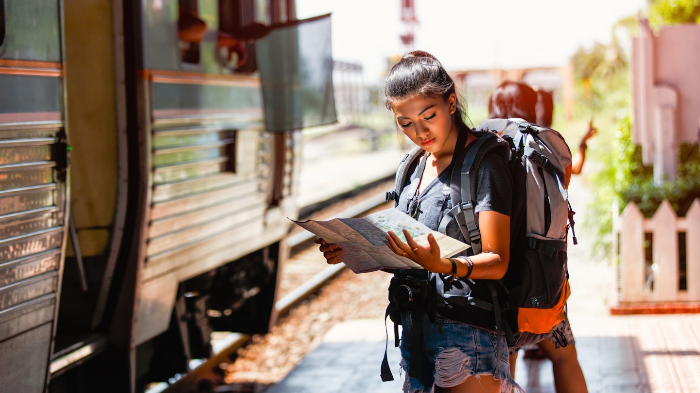 1053803902
horizontal image
A woman standing on a railway platform reading a map in Thailand