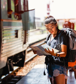 1053803902
horizontal image
A woman standing on a railway platform reading a map in Thailand