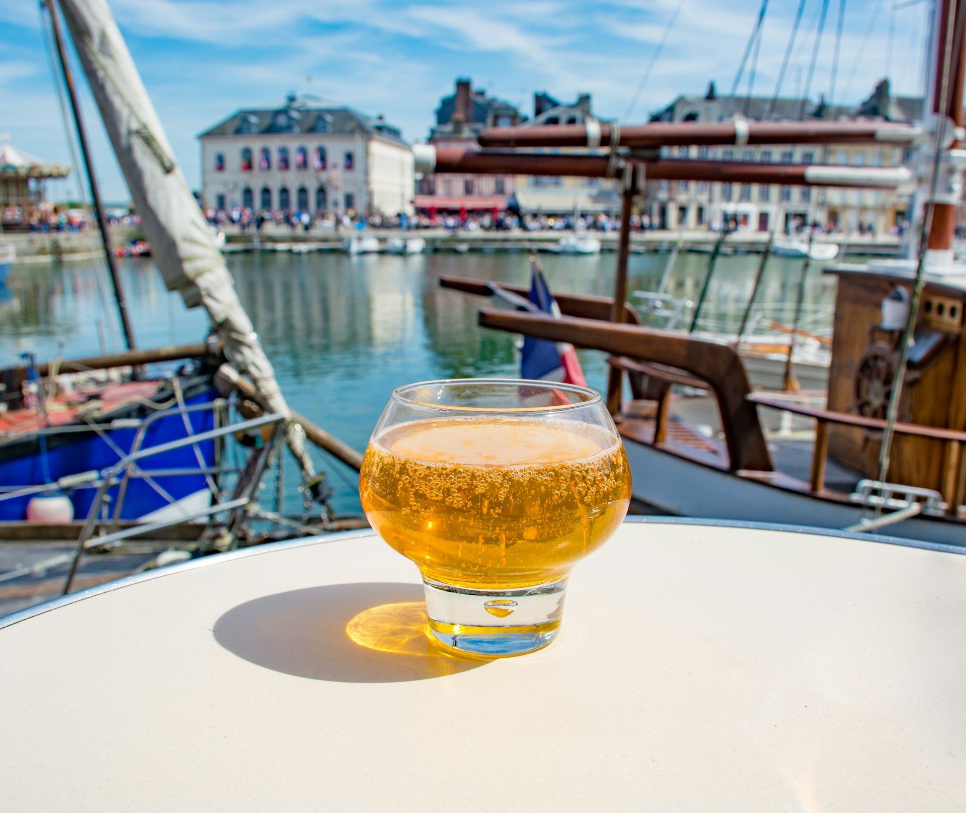 A glass of cider on a table by the harbor