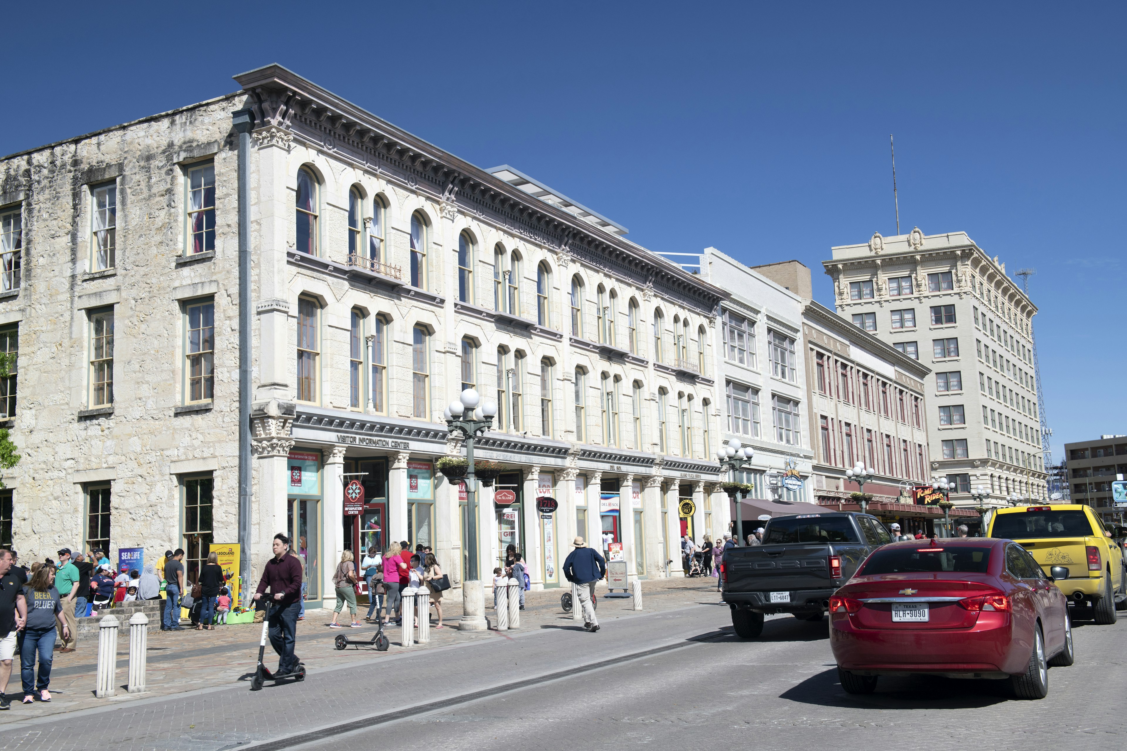 Traffic in Downtown San Antonio with people on the sidewalk on a sunny, blue-sky day