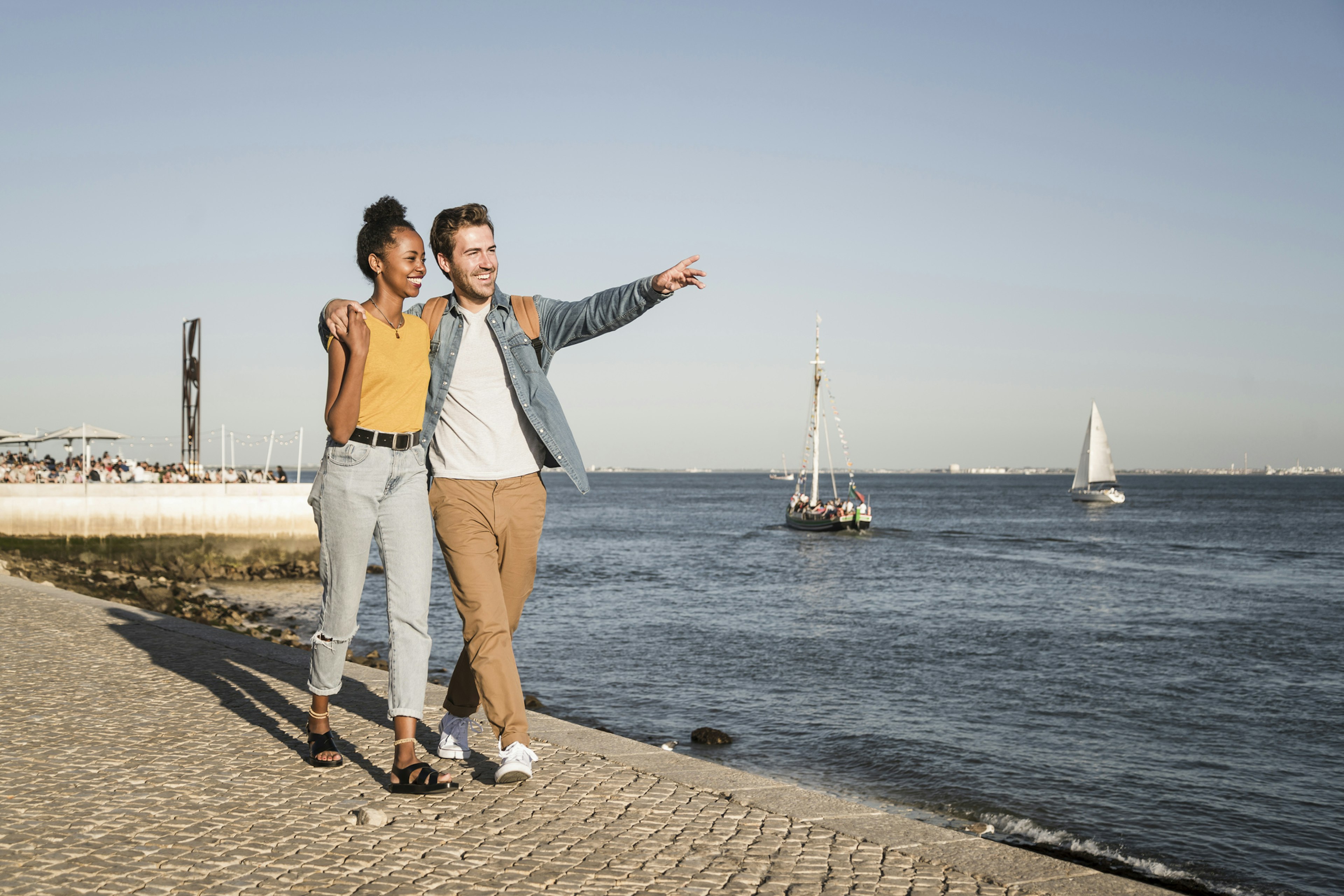 Happy young couple walking on pier at the waterfront, Lisbon, Portugal