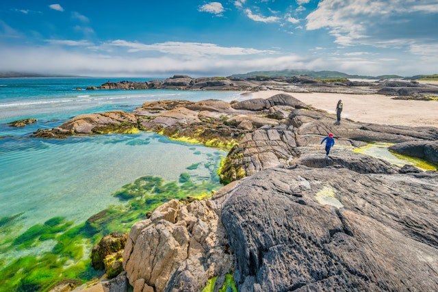 Mother and son enjoy the rocks of Derrynane beach on the Ring of Kerry, Ireland on a sunny day.
