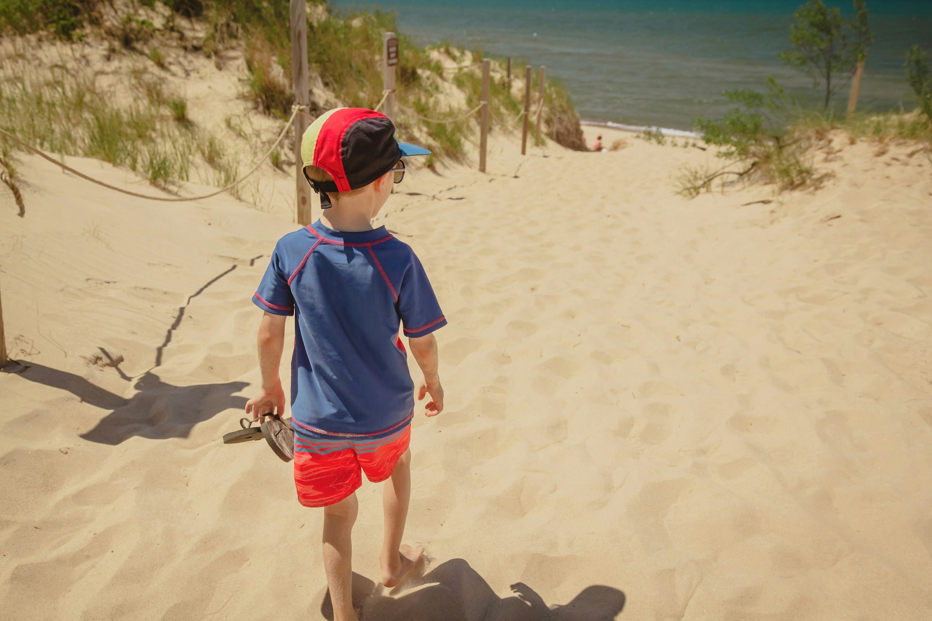 A young white boy walking along a white-sand dune toward West Beach in Indiana Dunes National Park