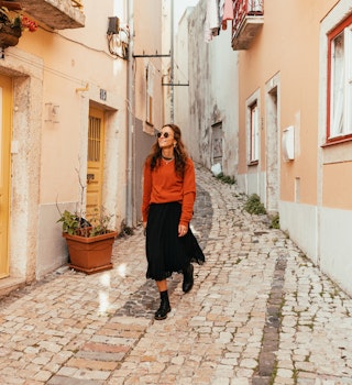 Young woman is walking around Lisbon city center, exploring the neighbourhood on foot
1360370392
A young woman walking along the cobbled streets of Lisbon