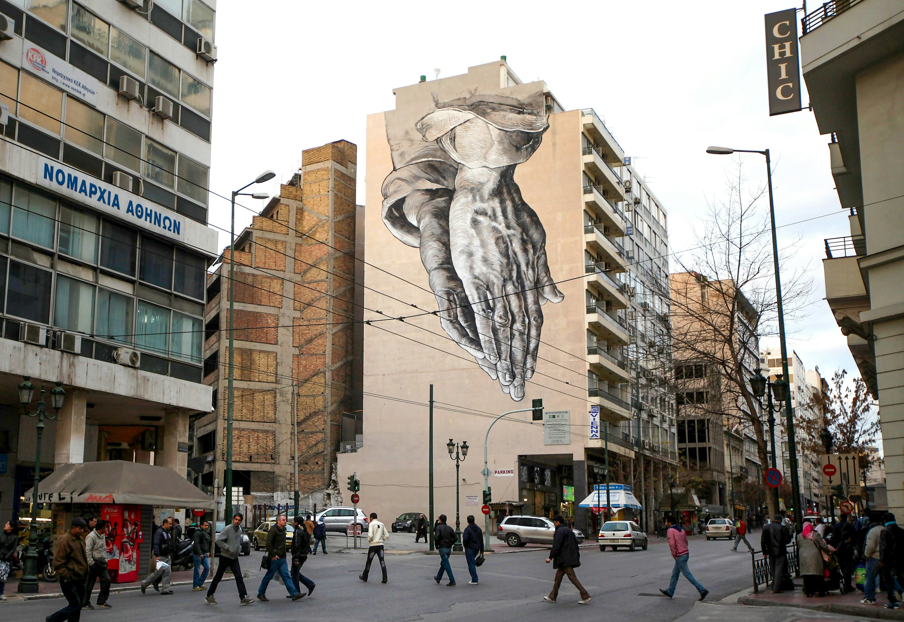 ATHENS, GREECE - FEBRUARY 18: Members of the public walk beneath a giant mural based on Albrecht Durer's 'Praying Hands' on February 18, 2012 in Athens, Greece. Following a meeting on Wednesday, finance ministers across the Eurozone are calling for greater scrutiny and oversight of Greece's proposed budget cuts in order to approve the latest 130 billion euro bailout package. The package, which is anticipated to be finalised on February 20, 2012, is essential for Greece to avoid defaulting on a 14.5 billion euro bond it is due to repay in mid-March.   (Photo by Oli Scarff/Getty Images)
139271791