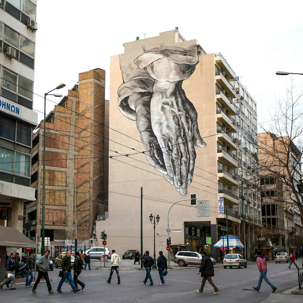 ATHENS, GREECE - FEBRUARY 18: Members of the public walk beneath a giant mural based on Albrecht Durer's 'Praying Hands' on February 18, 2012 in Athens, Greece. Following a meeting on Wednesday, finance ministers across the Eurozone are calling for greater scrutiny and oversight of Greece's proposed budget cuts in order to approve the latest 130 billion euro bailout package. The package, which is anticipated to be finalised on February 20, 2012, is essential for Greece to avoid defaulting on a 14.5 billion euro bond it is due to repay in mid-March.   (Photo by Oli Scarff/Getty Images)
139271791