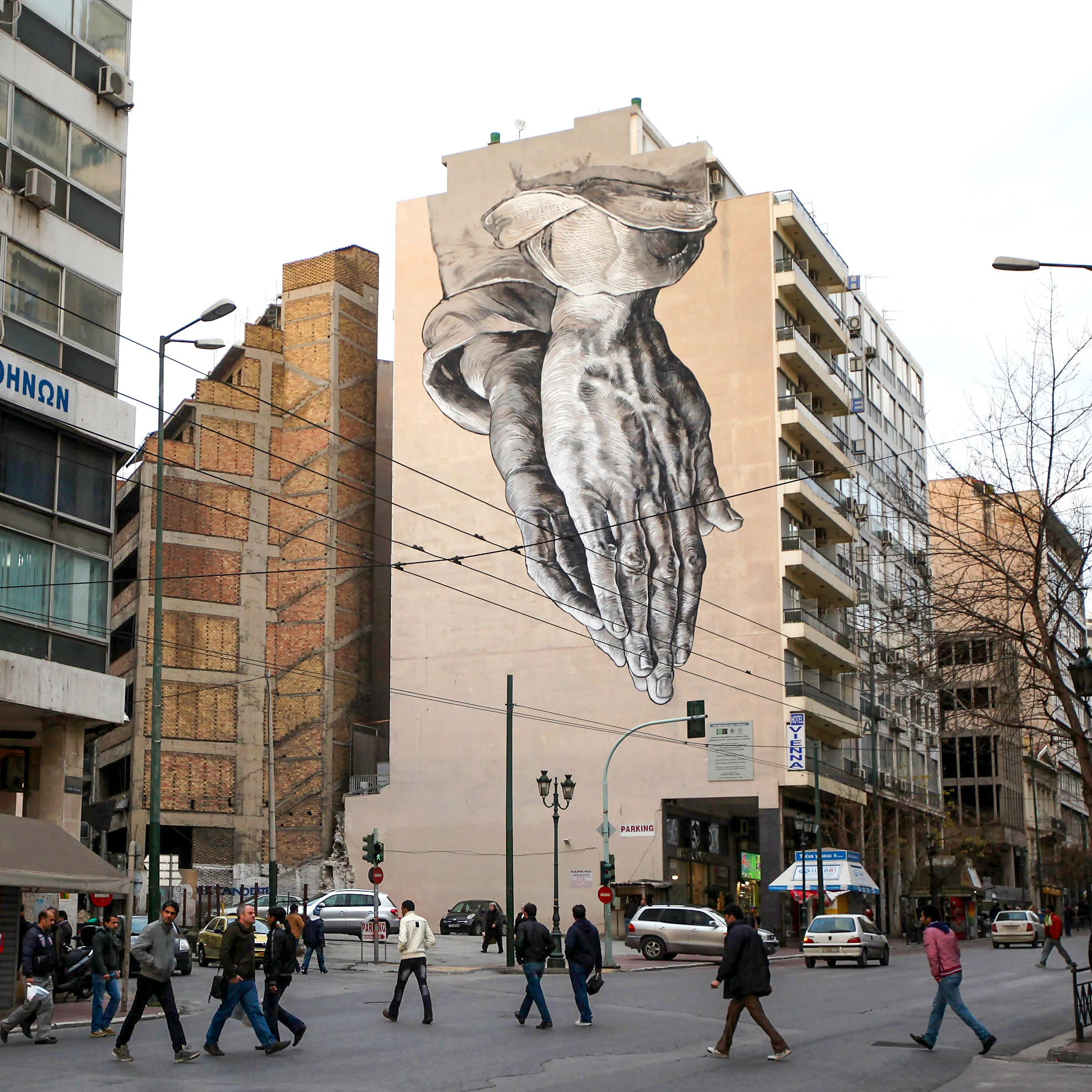 ATHENS, GREECE - FEBRUARY 18: Members of the public walk beneath a giant mural based on Albrecht Durer's 'Praying Hands' on February 18, 2012 in Athens, Greece. Following a meeting on Wednesday, finance ministers across the Eurozone are calling for greater scrutiny and oversight of Greece's proposed budget cuts in order to approve the latest 130 billion euro bailout package. The package, which is anticipated to be finalised on February 20, 2012, is essential for Greece to avoid defaulting on a 14.5 billion euro bond it is due to repay in mid-March. (Photo by Oli Scarff/Getty Images)
139271791
