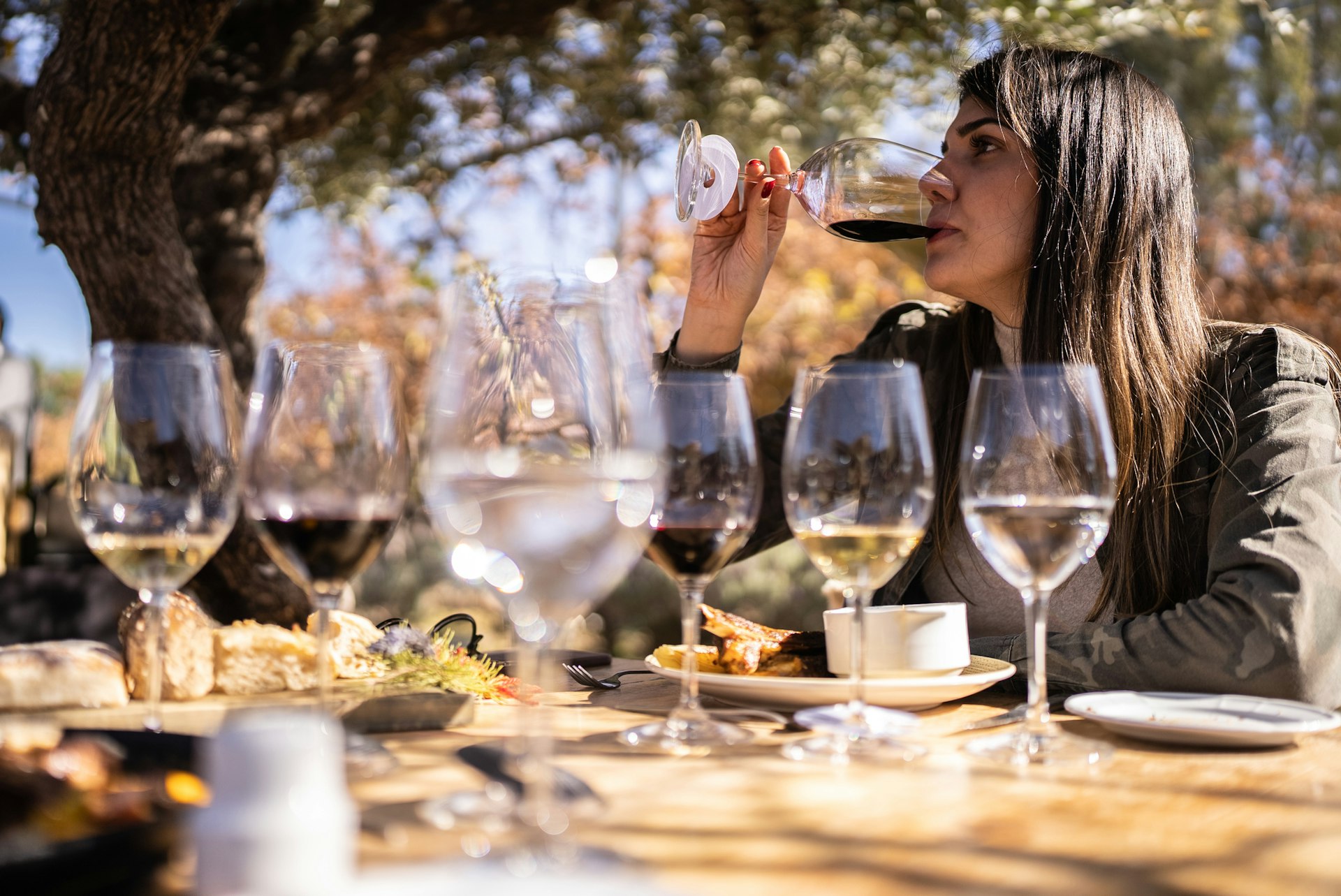 A women at a wine-tasting event is sipping red wine from the selection of white and red wines laid out on a table in front of her
