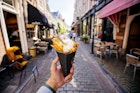 1440601751
A man holds out a cone filled with frites on an Amsterdam street