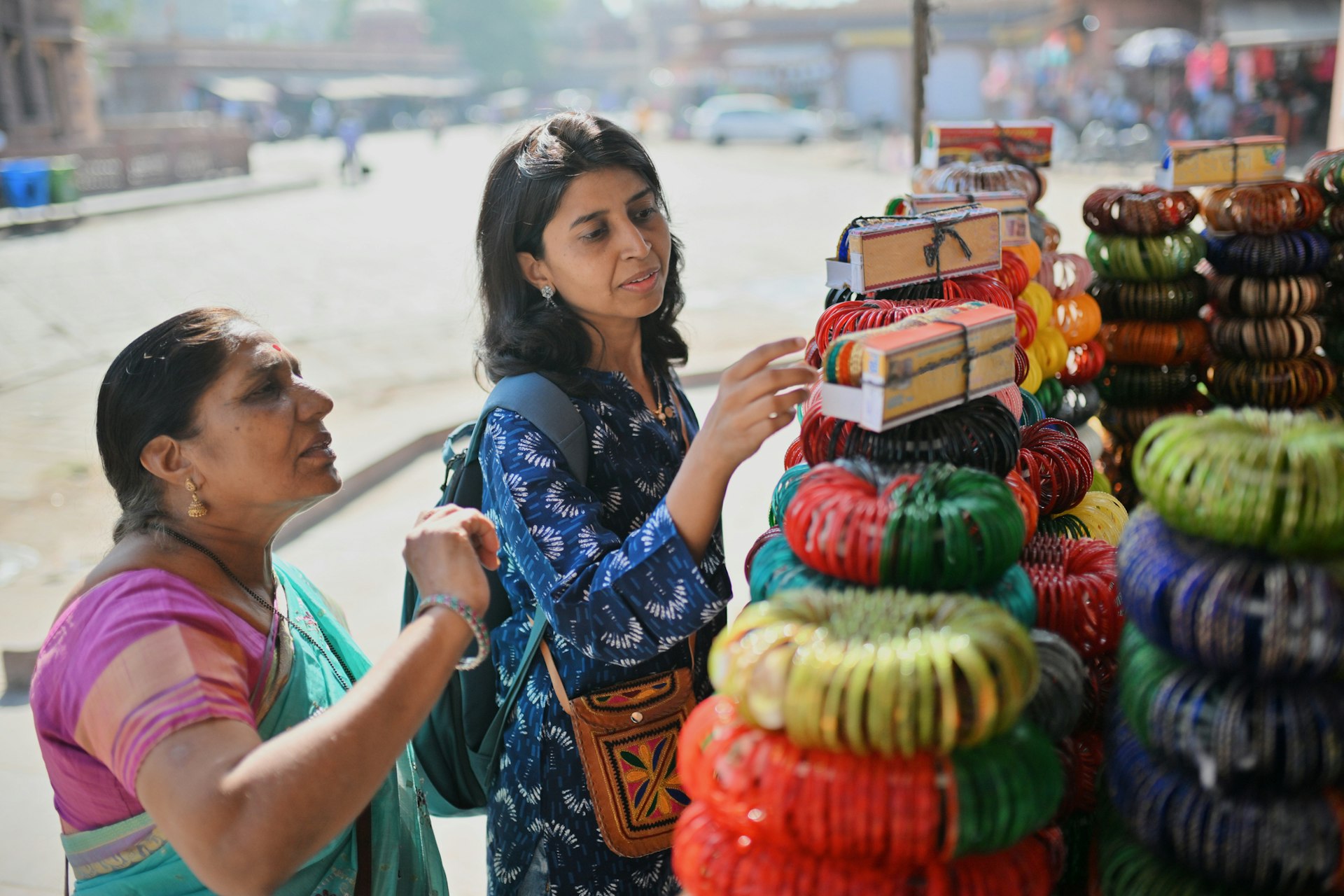 Two women tourists, a older mum and middle-aged daughter, browse bangles at a market in Jodhpur city, Rajasthan with a river in the background