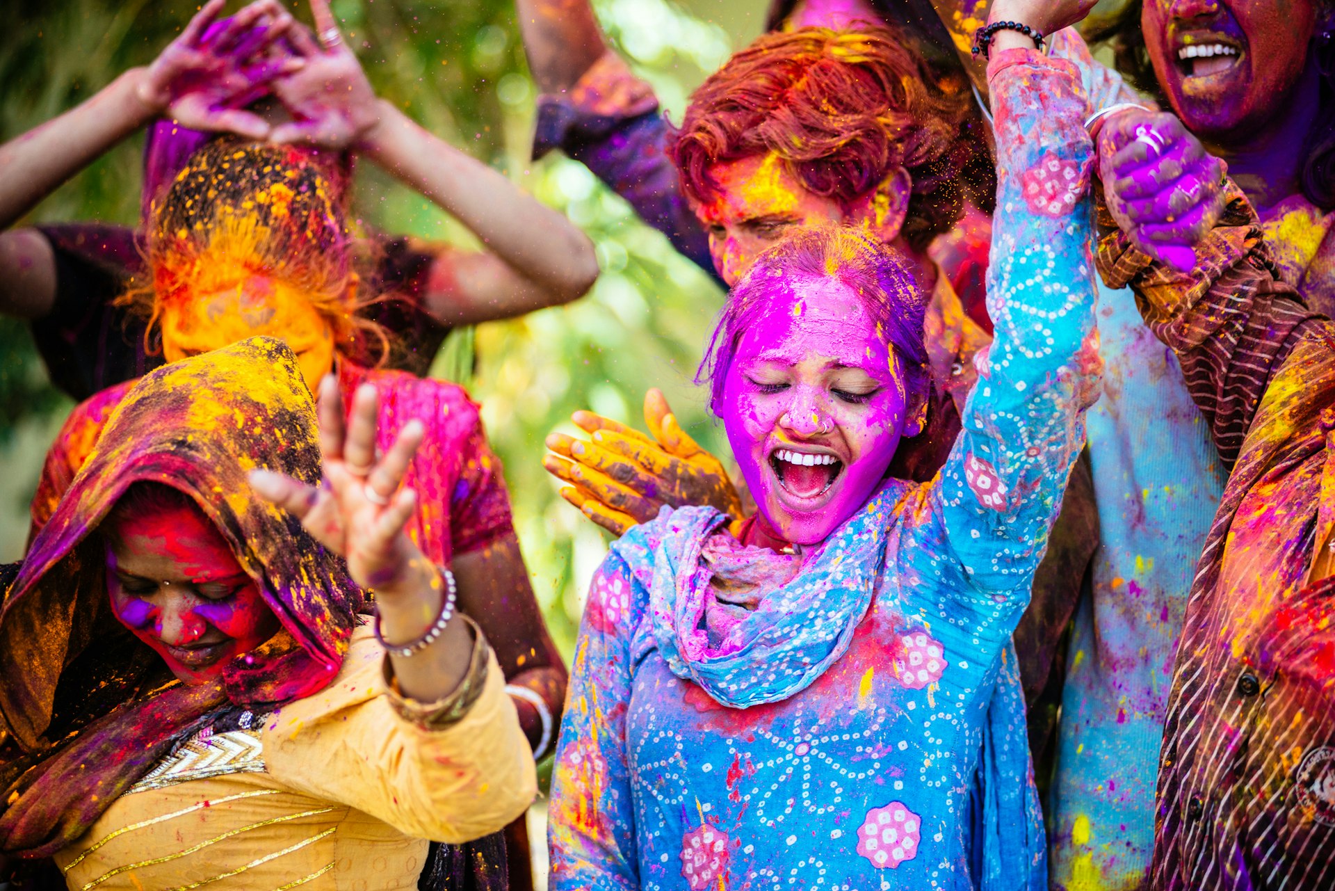 Women in India dancing during Holi covered in colorful powder