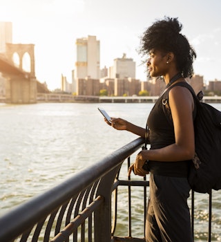 769732881
mobile phone, standing, bridge, River, woman, communication, phone, water, people, Adults, curly, backpack, summer, relaxed, black, leisure, urban, on the move, Connection, View, Travel, skyscraper, sky, sunlight, sunset, outdoors, side view, Backlit, day, Skyline, technology, urban scene, casual, three-quarter length, promenade, Afro, copy space, relaxation, accessibility, lifestyle, journey, wireless, Railing, riverside, top, Brooklyn Bridge, City Break, East River, Looking At View, Lens Flare, Waterfront, Traveller, cityscape, Smartphone, female tourist, single traveler, mid adult woman, one person, 30-34 years, African descent, African-American Ethnicity, female Afro-American, Brooklyn, colour, city, built structure, building, high-rise, sunshine, atmosphere, city view, waters edge, tourism, looking, tourist, mid adults, 30-40 years, USA, New York State, New York City, Photography, Color Image
A woman standing on the waterfront of the Hudson River with the Manhattan skyline in the background