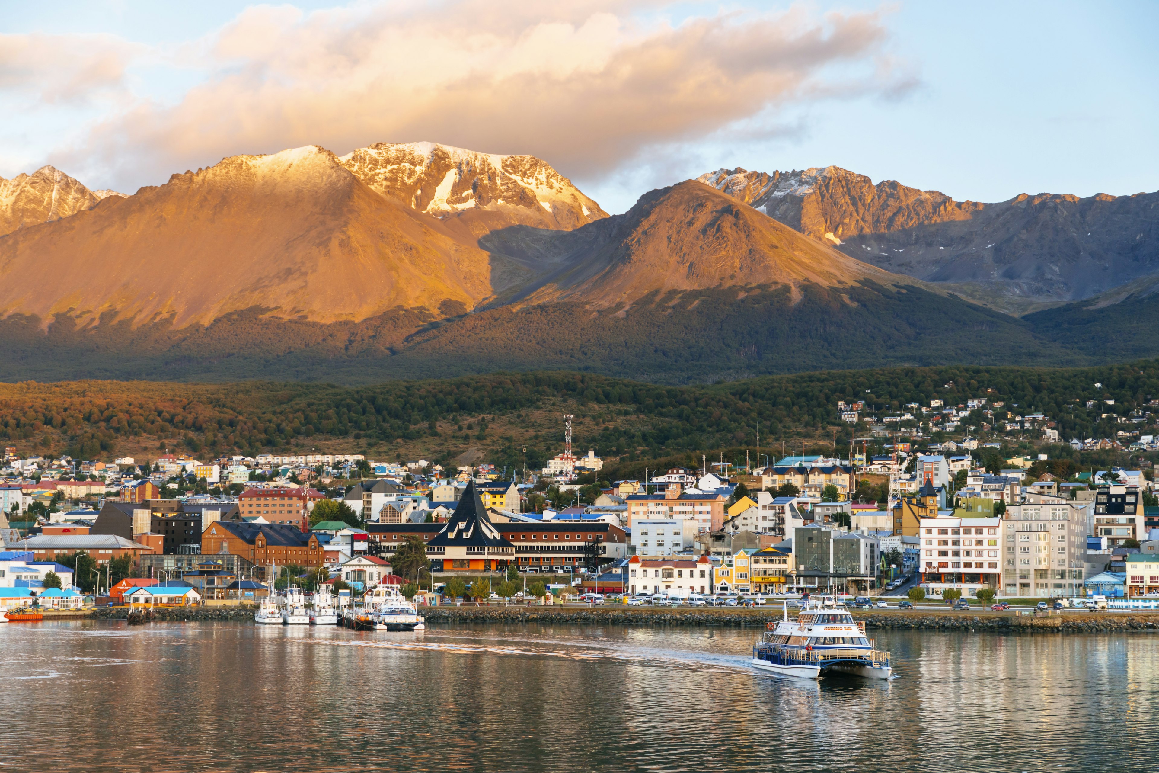 Boats head out of a port backed by mountains