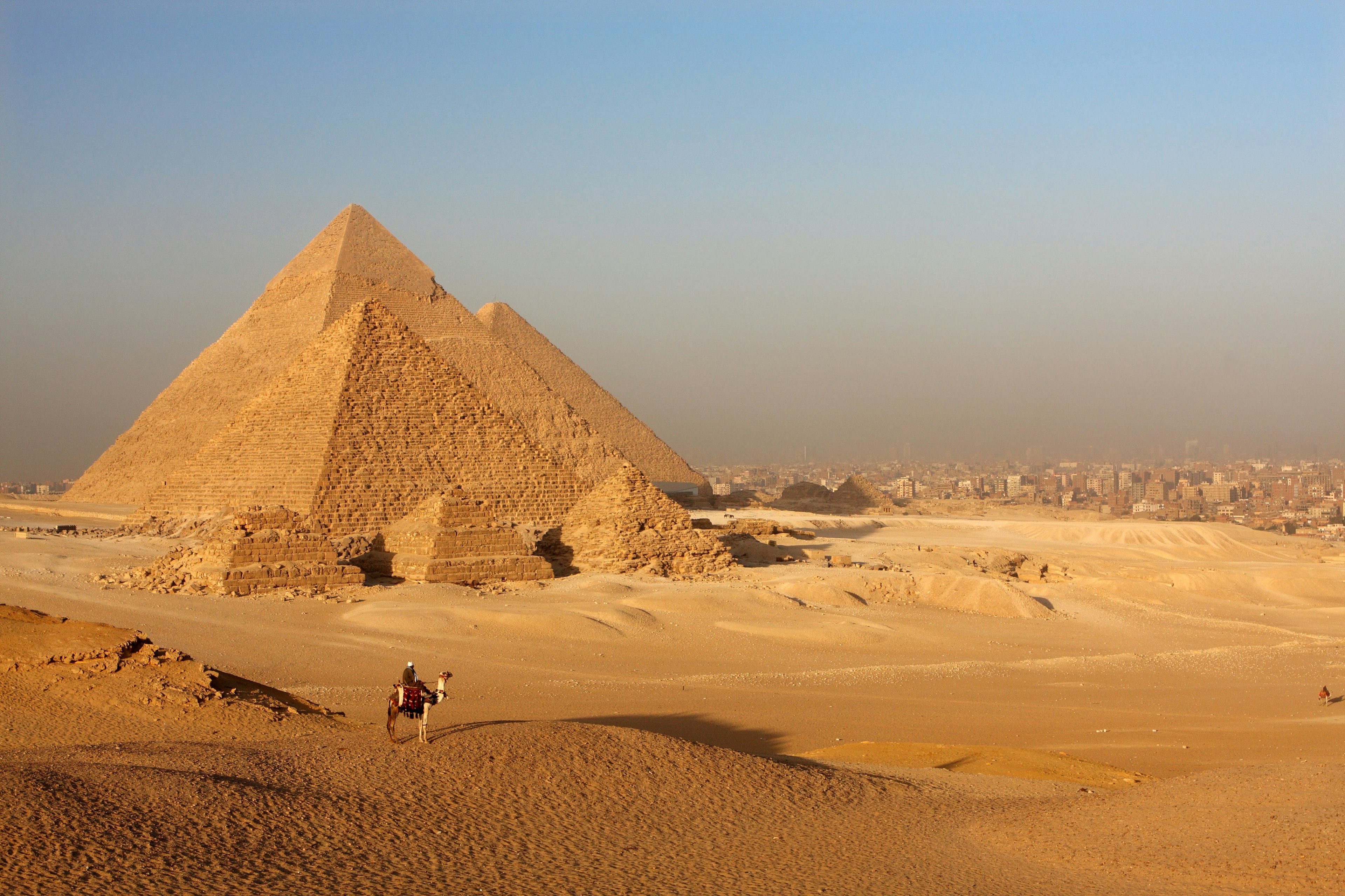 Pyramids in the Egyptian desert, with a person riding a camel.