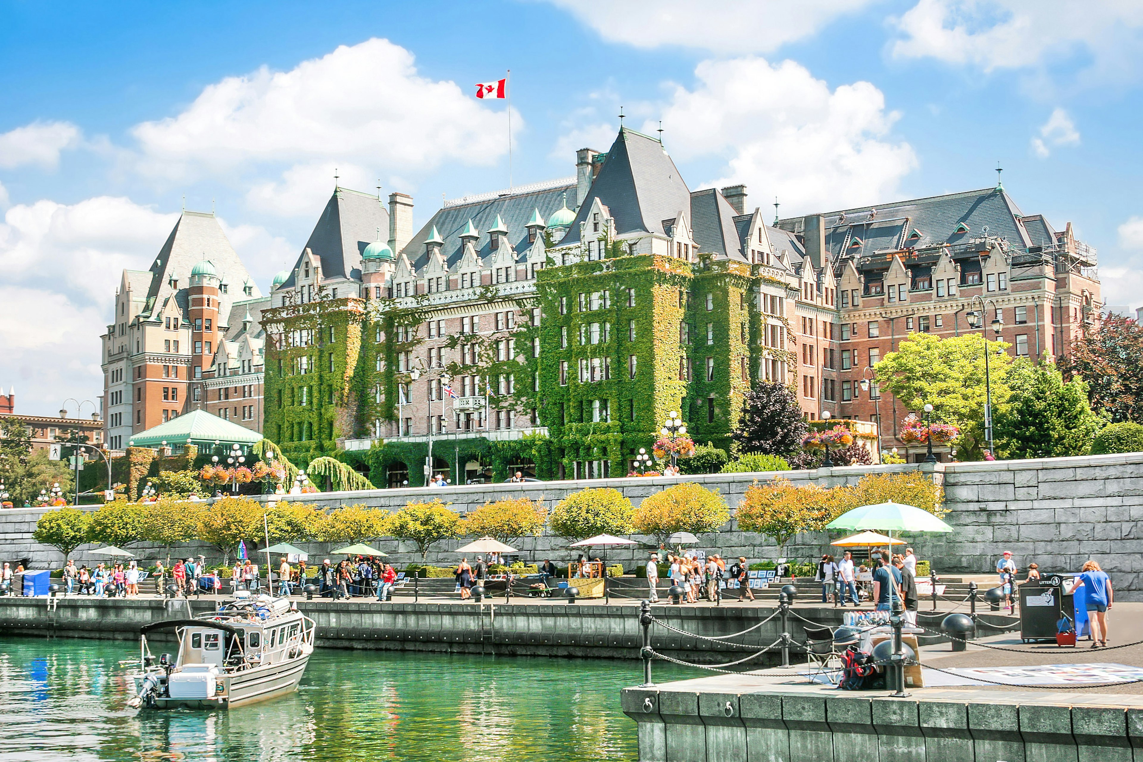 A Canadian flag flies above a large ivy-covered building on the waterfront